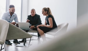 Three people having a discussion around a computer