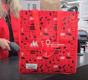 An Ace Hardware staff member scanning a reusable carry bag at the checkout