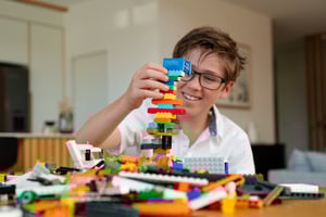 A young boy is building a tower made of NovaBrix building bricks