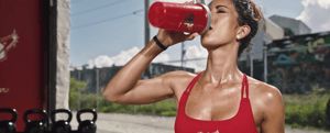 A woman drinking out of a Novelli Glanbia Protein Shaker 